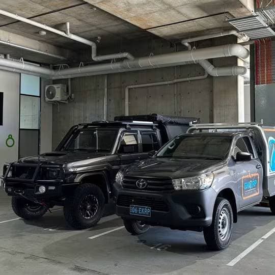Two plumbing service vehicles in a covered parking area