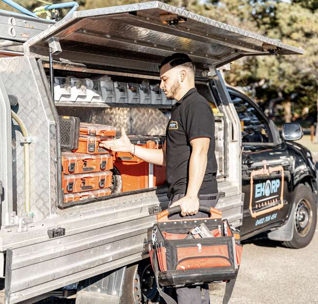 A plumber collecting tools from the service vehicle