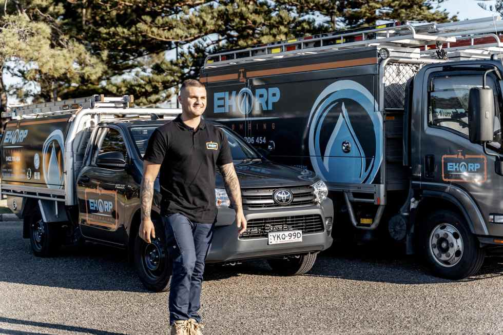 A plumber standing beside the service vehicles
